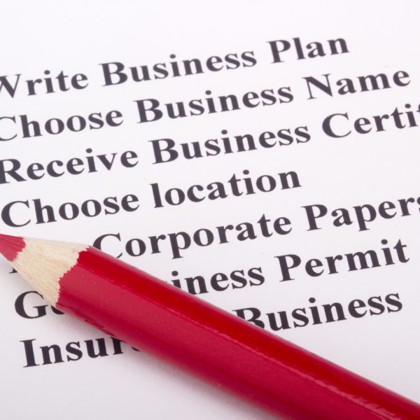 A red pencil laying on a paper with a checklist for starting a business.