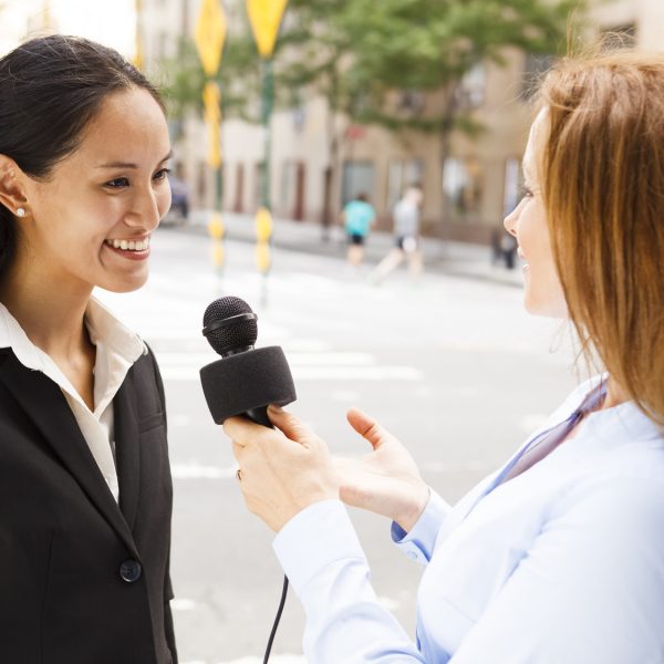 A reporter with a microphone interviews a woman.