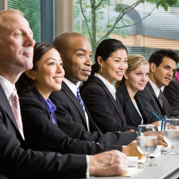Multi-ethnic co-workers sitting in a row at conference table